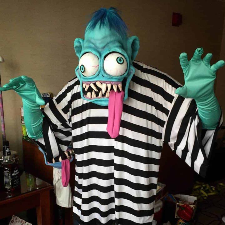 Teal Weird-Oh mask with tongue out, worn with a striped shirt